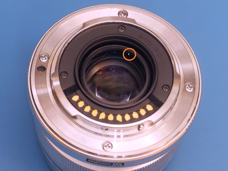 Rear of 12mm lens with small metal flake on rear lens element.